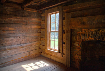 Interior log cabin window looking outward with sunlight shining in from an angle