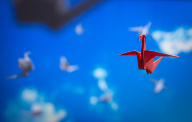 colored origami bird flying in the blue sky