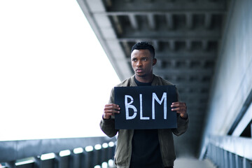 Man with BLM sign standing outdoors, black lives matter concept.
