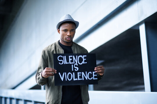 Man with silence is violence sign standing outdoors, black lives matter concept.