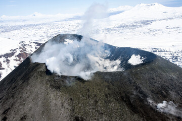 Fototapeta na wymiar The mouth of an active volcano, with smoke and steam, when flying it by helicopter.