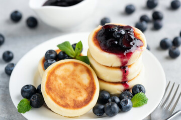 Cottage cheese fritters with blueberry jam on white plate. Russian, Ukrainian cuisine. Sweet syrniki, fried cheese pancakes