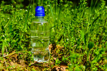 Plastic bottle with the clear water in green grass