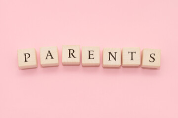 The word PARENTS is made of wooden cubes on a pink background.