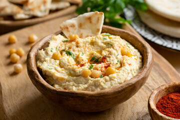 Homemade chickpea hummus bowl with pita chips and smoked paprika. Closeup view, square crop