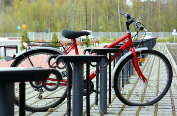 Lone abandoned red bike in a deserted bicycle parking lot.