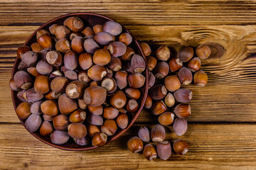 Plate with pile of hazelnuts on a wooden table. Top view