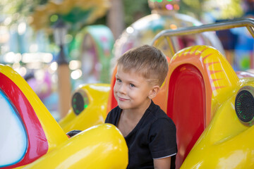 Fototapeta na wymiar a little boy in an amusement Park a child rides a toy car or robot
