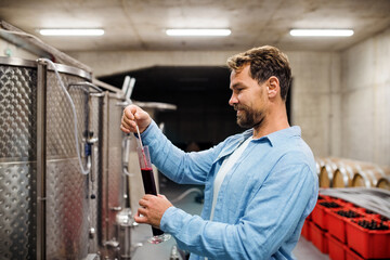 Man worker measuring gravity indoors, wine making concept.