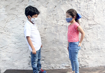 6-year-old boy and girl with covid-19 virus protection masks, on white wall background, new normal