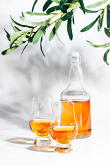Scotch Whiskey without ice in glasses and bottle, white background with hard light, shadows and sun glare, copy space