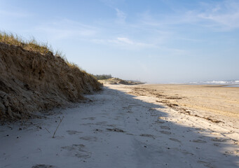 Dunas à beira mar com sol ao lado e nuvens bonitas