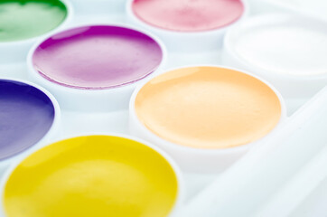 A set of close-up watercolors isolated on a white background. A palette of bright colors for drawing. Creative development for children and school children. Office supplies for September 1