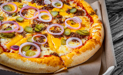 Pizza with Mozzarella cheese, Bolognese sauce, minced meat and vegetables. Italian pizza in paper box on wooden background.