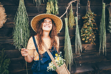 Attractive girl wearing straw hat and blue denim dungarees relaxing near bouquets of aromatic...