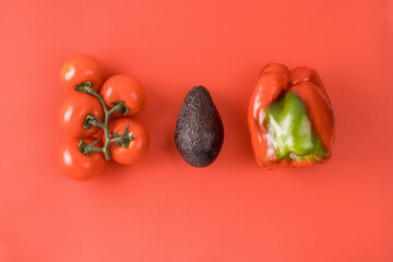 Layout made of avocado, tomato and pepper. Food concept. Vegetables on red background. Minimal summer concept. Vegetable design. Flat lay.