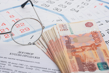 Sale and purchase agreement of an apartment, a wad of money, a calendar and glasses