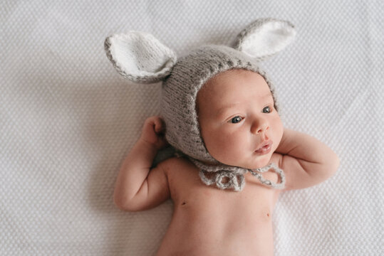 Curious newborn in funny knitted bonnet