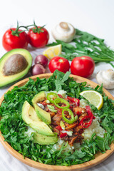 Healthy trendy vegan burrito bowl with white rice, spicy tomato mushroom mix, green arugula, lemon, and sliced avocado. Topped with red and green chili peppers and scallions