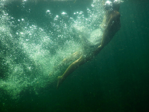 Woman covered in air bubbles swims in dark lake