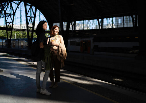 Two girlfriends waiting for a train together