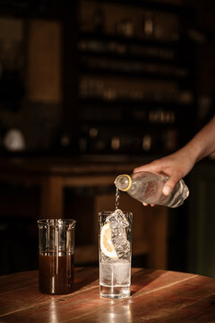 Female pouring water from bottle to glass with ice.