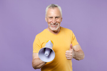 Smiling elderly gray-haired mustache bearded man in casual yellow t-shirt posing isolated on violet wall background studio portrait. People emotions lifestyle concept. Hold megaphone showing thumb up.