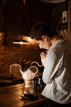 Professional female barista making coffee at bar.