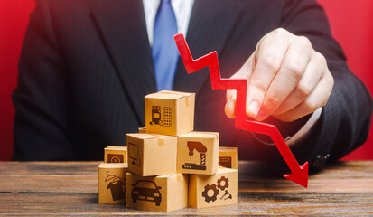 Businessman holds a red down arrow over the boxes. Business industrial production drop rate. Shortage of products. Low supply and demand, falling market recession, low delivery volumes. Overproduction