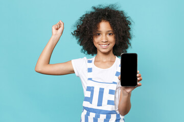 Joyful little african american kid girl 12-13 years old in striped clothes isolated on blue...