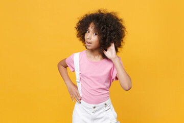 Shocked little african american kid girl 12-13 years old in pink t-shirt isolated on yellow...