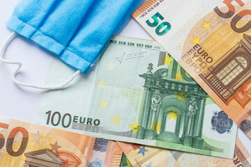 Medical face masks and money. Face mask on Euro banknotes bill background. Crisis, Covid-19.