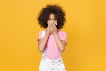 Fototapeta na wymiar Little african american kid girl 12-13 years old in pink t-shirt isolated on yellow background children studio portrait. Childhood lifestyle concept. Mock up copy space. Covering mouth with hands.