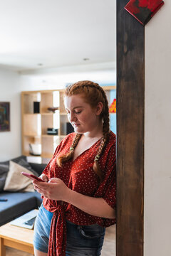Red haired woman texting inside the house laying on the wall