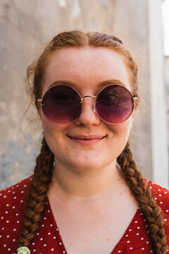 close up of a smiling woman with her red hair down in sunglasses