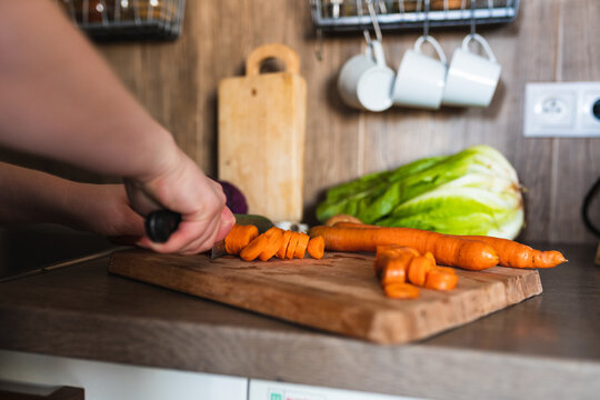 close up of a hand cutting the carrots with a knife.