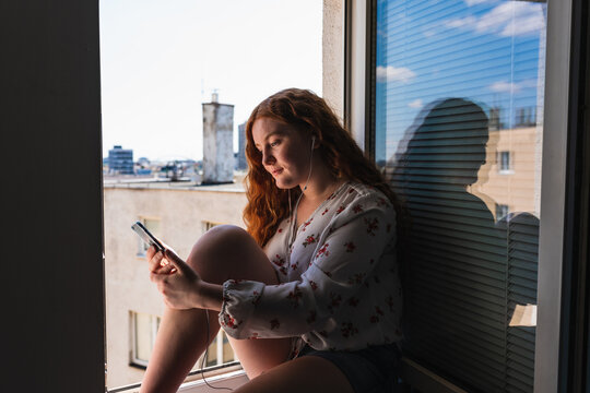Relaxed red hair woman listen a podcast on her phone