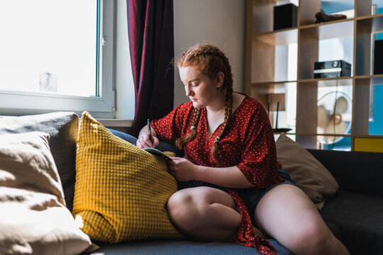 red haired woman with her hair in braids witting on the couch