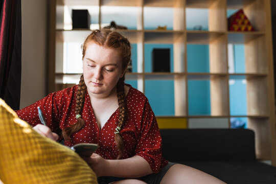 woman with her hair in braids writting on a notebook.