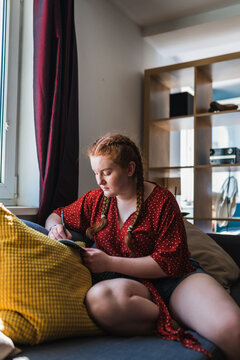 red haired woman with her hair in braids witting on the couch