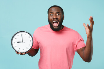 Worried young african american man guy in casual pink t-shirt isolated on blue background studio...