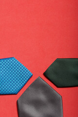 Men's ties in different colors and sizes. For father and sons. Love and Togetherness Objects. On a coral background.