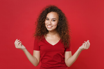 Smiling young african american woman girl in casual t-shirt posing isolated on red wall background....