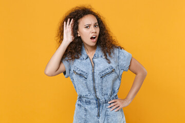 Shocked young african american woman girl in casual denim clothes isolated on yellow wall...