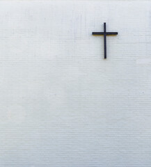 Metallic cross on a white new plastered brick wall, viewed from the front. Generic church wall...