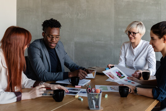 Positive multiethnic employees discussing project in conference room