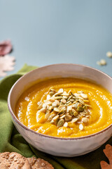 Delicious pumpkin soup with pumpkin seeds in bowls on a dark gray background, copy space. Free space for text. Autumn food. Thanksgiving food.