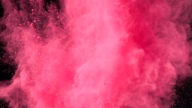 Super slow motion explosion of colorful red powder on dark isolated background. Lumps of powder fly upwards and mix with the smoke.