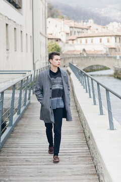 Trendy young male walking on bridge