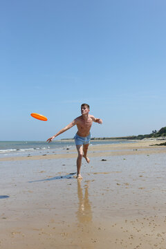 Young man playing frisbee on the beach
